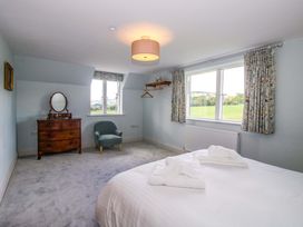 A bedroom with a bed, armchair, and window at Hoddell Pitch Cottage in Kinnerton near New Radnor