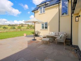 An outdoor patio with seating and an umbrella at Hoddell Pitch Cottage in Kinnerton near New Radnor