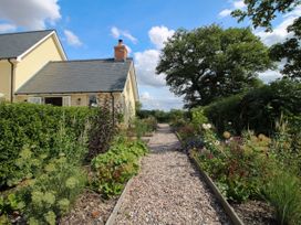A garden with a pathway lined with flowers at Hoddell Pitch Cottage in Kinnerton near New Radnor