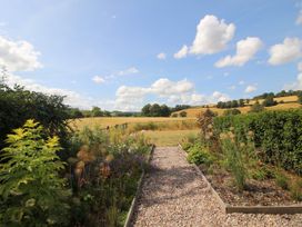 A garden with a gravel path leading to an open field at Hoddell Pitch Cottage Kinnerton near New Radnor