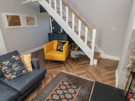 A living room with a yellow chair blue sofa patterned rug and stairs at Min-Y-Ffordd in Dinas Cross