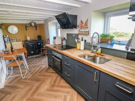 A kitchen with wooden countertops blue cabinets a double sink and a dining table with chairs at Min-Y-Ffordd in Dinas Cross