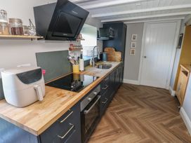 A kitchen with wooden countertop black cabinets a stove oven sink and white door at Min-Y-Ffordd in Dinas Cross