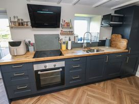 A kitchen with dark cabinets wooden countertop stove oven microwave and a sink at Min-Y-Ffordd in Dinas Cross
