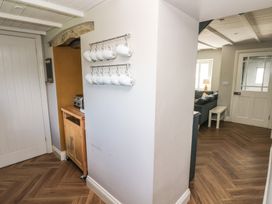 A hallway with white mugs hanging on a wall wooden floor and a view into a living room at Min-Y-Ffordd in Dinas Cross