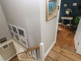 A staircase with framed pictures on the walls and a small room with a vanity table and stool at Min-Y-Ffordd in Dinas Cross