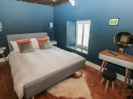 A bedroom with a bed with pillows bedside tables a window with shutters and a dressing table with a stool at Min-Y-Ffordd in Dinas Cross