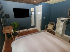 A bedroom with a bed desk floor lamp mirror chair and shelving unit at Min-Y-Ffordd in Dinas Cross