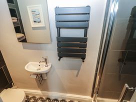 A small bathroom with a sink toilet towel radiator and shower at Min-Y-Ffordd in Dinas Cross