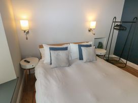 A bedroom with a bed with pillows two bedside tables with lamps and a clothes rack at Min-Y-Ffordd in Dinas Cross