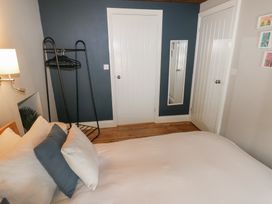 A bedroom with a bed pillows a standing clothes rack two closed doors and a wall mirror at Min-Y-Ffordd in Dinas Cross