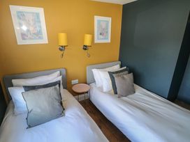 A bedroom with two single beds separated by a small round table and yellow wall lights at Min-Y-Ffordd in Dinas Cross