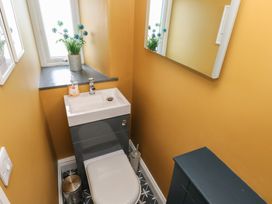 A small bathroom with a toilet and sink combination unit next to a window with a plant on the sill and a mirror on the wall at Min-Y-Ffordd in Dinas Cross