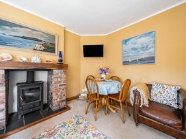 A living room with a dining table and a fireplace at Bodior Lodge in Rhoscolyn