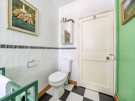 A bathroom with a toilet and wall art at Bodior Lodge in Rhoscolyn
