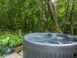 A hot tub in a garden surrounded by trees at Bodior Lodge in Rhoscolyn