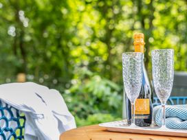 Bottle of Prosecco and glasses on a tray in an outdoor seating area at Bodior Lodge Rhoscolyn