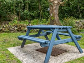 A picnic table on a grassy area next to a tree at Bodior Lodge Rhoscolyn
