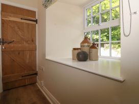 A wooden door next to a window with four ceramic jugs and a decorative object on the windowsill at Bodior Garden Cottage in Rhoscolyn
