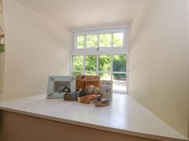 A window sill with a framed picture basket decorative duck figurines and a book at Bodior Garden Cottage in Rhoscolyn