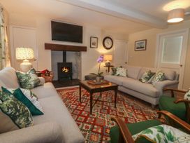 A living room with two sofas green armchairs and a patterned rug at Bodior Garden Cottage in Rhoscolyn