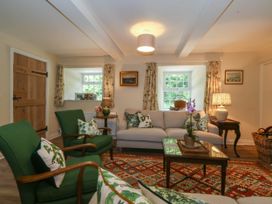 A living room with green armchairs a beige sofa and a patterned rug at Bodior Garden Cottage in Rhoscolyn