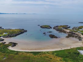A beach with calm waters and scattered rocks at Bodior Garden Cottage in Rhoscolyn