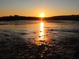 Sunrise over water with rocks at Bodior Garden Cottage Rhoscolyn