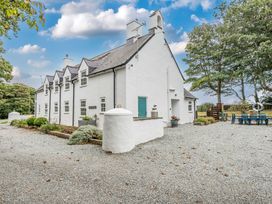 An outdoor view of a house with a gravel driveway and garden furniture at Bodior Garden Cottage in Rhoscolyn