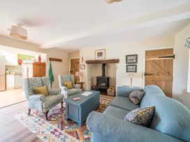 A living room with a stove and armchairs at Bodior Garden Cottage in Rhoscolyn