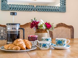 A dining table with coffee and pastries at Bodior Garden Cottage in Rhoscolyn