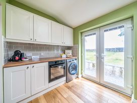 A kitchen with cabinets and appliances at Bodior Garden Cottage Rhoscolyn
