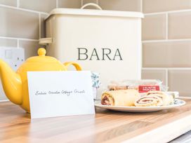 A kitchen with a yellow teapot and a plate of Swiss rolls at Bodior Garden Cottage in Rhoscolyn