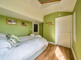 A bedroom with a bed and framed pictures at Bodior Garden Cottage Rhoscolyn