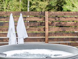 A hot tub with towels hanging on a wooden fence at Bodior Garden Cottage Rhoscolyn