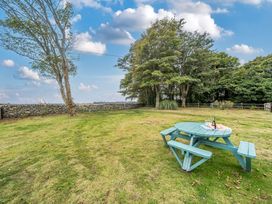 A picnic table with wine and glasses in a garden at Bodior Garden Cottage Rhoscolyn
