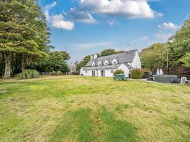 An outdoor view of a house with a lawn and patio at Bodior Garden Cottage in Rhoscolyn