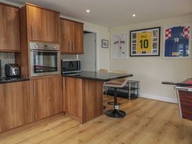 A kitchen with wood cabinets and bar stools at Whimhowe in Windermere