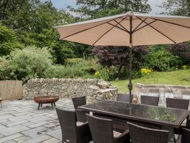 An outdoor dining table with chairs and an umbrella at Whimhowe in Windermere