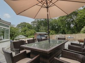 A garden with a table and chairs under an umbrella at Whimhowe in Windermere