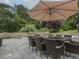 An outdoor patio with a dining table and chairs under a parasol at Whimhowe in Windermere