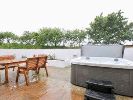 An outdoor area with a hot tub and wooden furniture at The Dairy Barn in Camelford