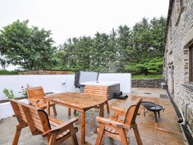 An outdoor area with a table and chairs next to a hot tub at The Dairy Barn in Camelford