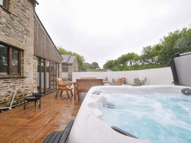 A garden with a hot tub and wooden furniture at The Dairy Barn in Camelford