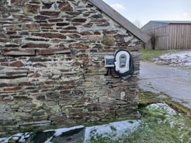 An electric vehicle charger mounted on a stone wall in an outdoor area at The Dairy Barn in Camelford