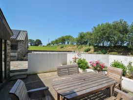 An outdoor seating area with wooden table and flowers at The Dairy Barn in Camelford