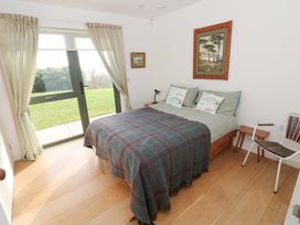 A bedroom with a bed and a chair at Green Shutters in Freshwater East near Lamphey