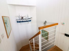 A stairwell with a model boat and framed pictures at Green Shutters Freshwater East near Lamphey