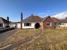 A bungalow with a brick and white exterior and a front lawn at Bayview Cottage in Southbourne