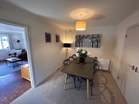 A dining room with a table and chairs and a plant in the center and a black floor lamp in the corner at Bayview Cottage in Southbourne